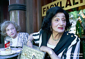 Two elegant, well-dressed attractive old ladies sit down in Müvés Café, a famous Andrasszy Street cafe in Budapest, Hungary.