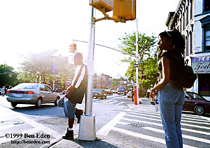 A black teenager waits leaning against a traffic light pole on the corner of Park PL and Flatbush Avenue in Brooklyn, New York, USA