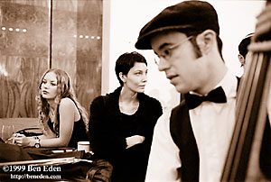 A Jewish double base player plays klezmer jazz while two young Jewish women listen, poised on the piano during a Chanukah (Hanukah) ball in Prague, Czech Republic