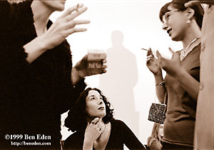 Three young Czech Jewish women smoke Pall Mall cigarettes and chat at a Chanukah (Hanukah) ball given in the Rudolf Gallery at Prague Castle. Shade behind is cast by statue of Tomas (Thomas) Garrigue Masaryk.