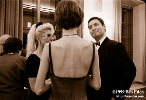 Young Jewish woman in a bare-back dress watches a gentleman make a face at Chanukah (Hanukah) charity ball held in the Rudolph Gallery at Prague Castle, Czech Republic.