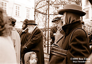 An older Jewish couple stands on Male namesti, waiting for the big outdoor Menorah to be lit while Rabbi Manis Barash stands in the bacground at a Chanukah (Hanukah) celebration held in Prague, Czech Republic Jewish Community's eating hall.